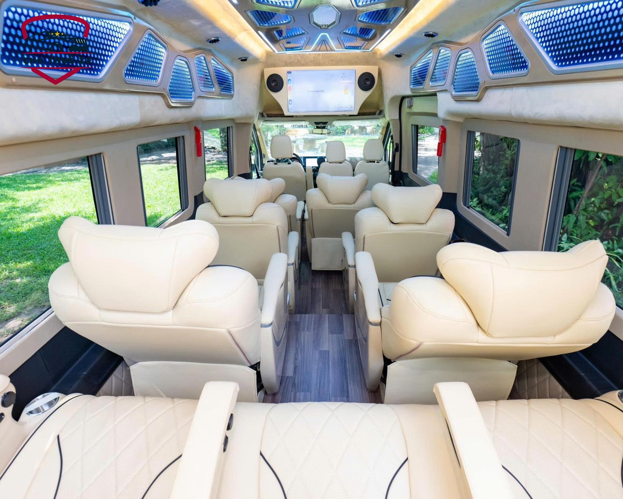 Khoang hành khách của xe limousine 12 chỗ nhìn từ phía sau, với các hàng ghế đơn bọc da màu kem bố trí thoải mái, lối đi rộng rãi và cửa sổ lớn cung cấp ánh sáng tự nhiên