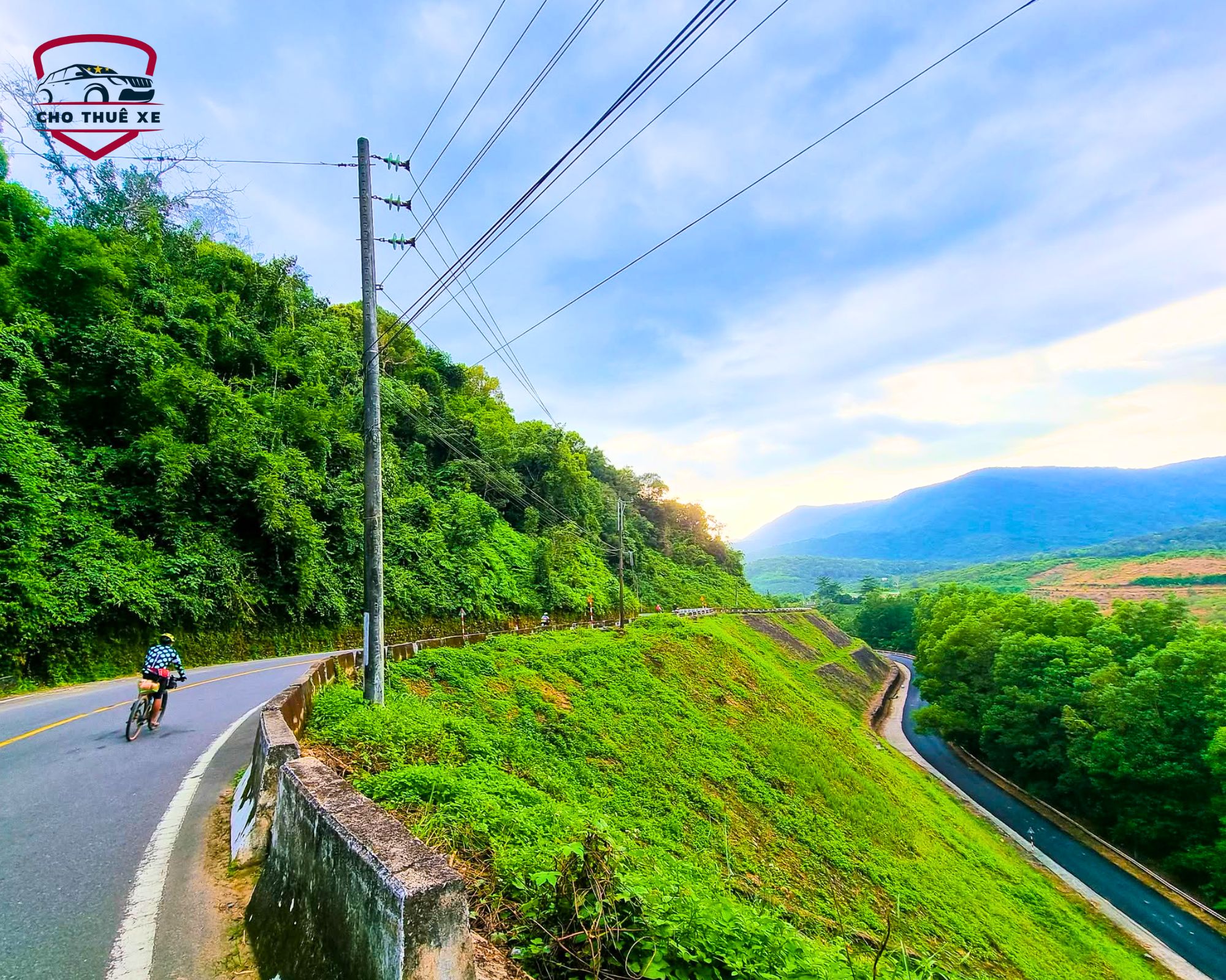 Khung cảnh đèo Tà Pứa thanh bình, con đường nhựa ôm lấy sườn đồi xanh nghiêng thoải xuống thung lũng bên dưới
