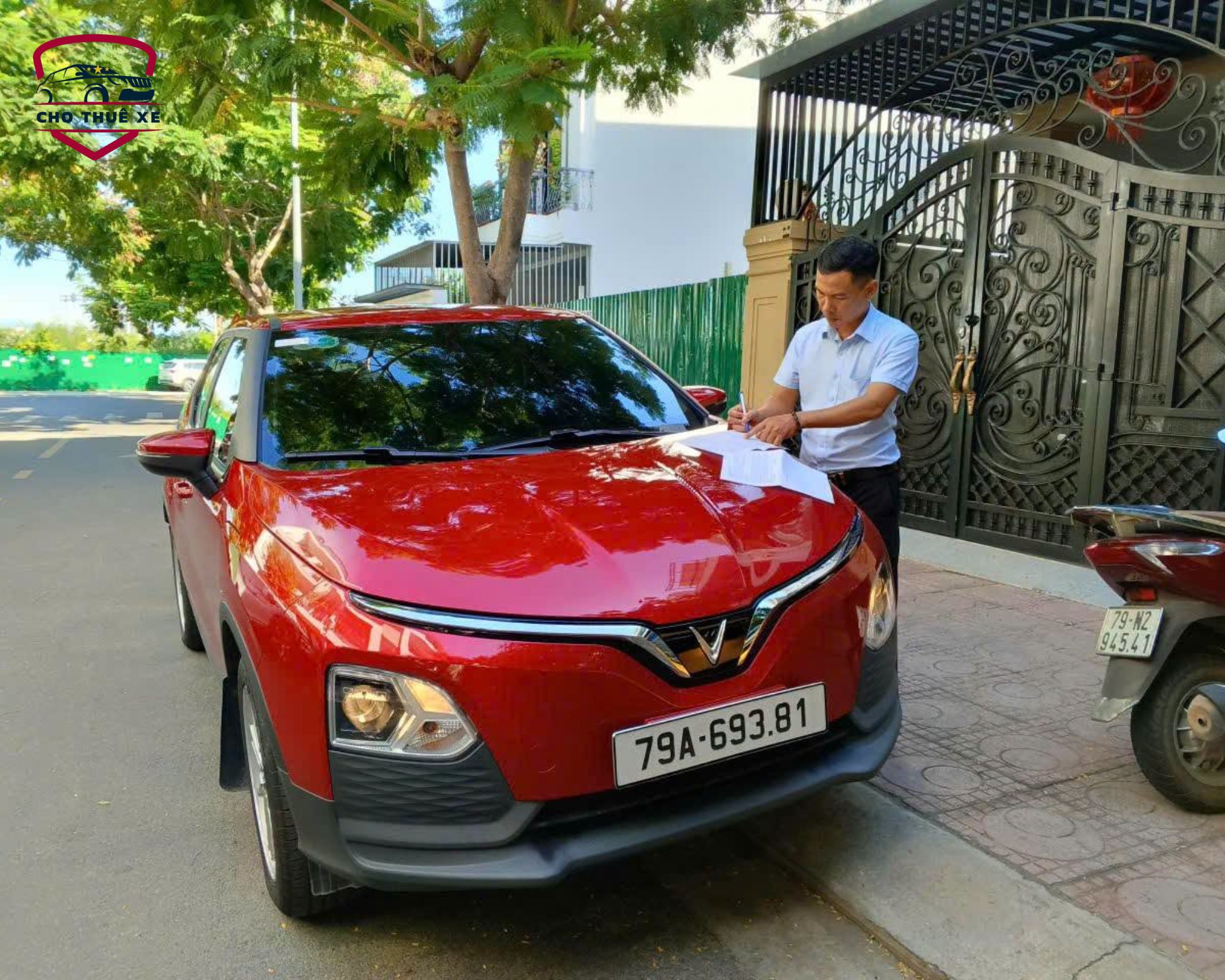 Nhân viên hỗ trợ khách hàng hoàn tất thủ tục nhận xe màu đỏ ngay tại đường phố, đảm bảo khởi hành thuận lợi và an tâm