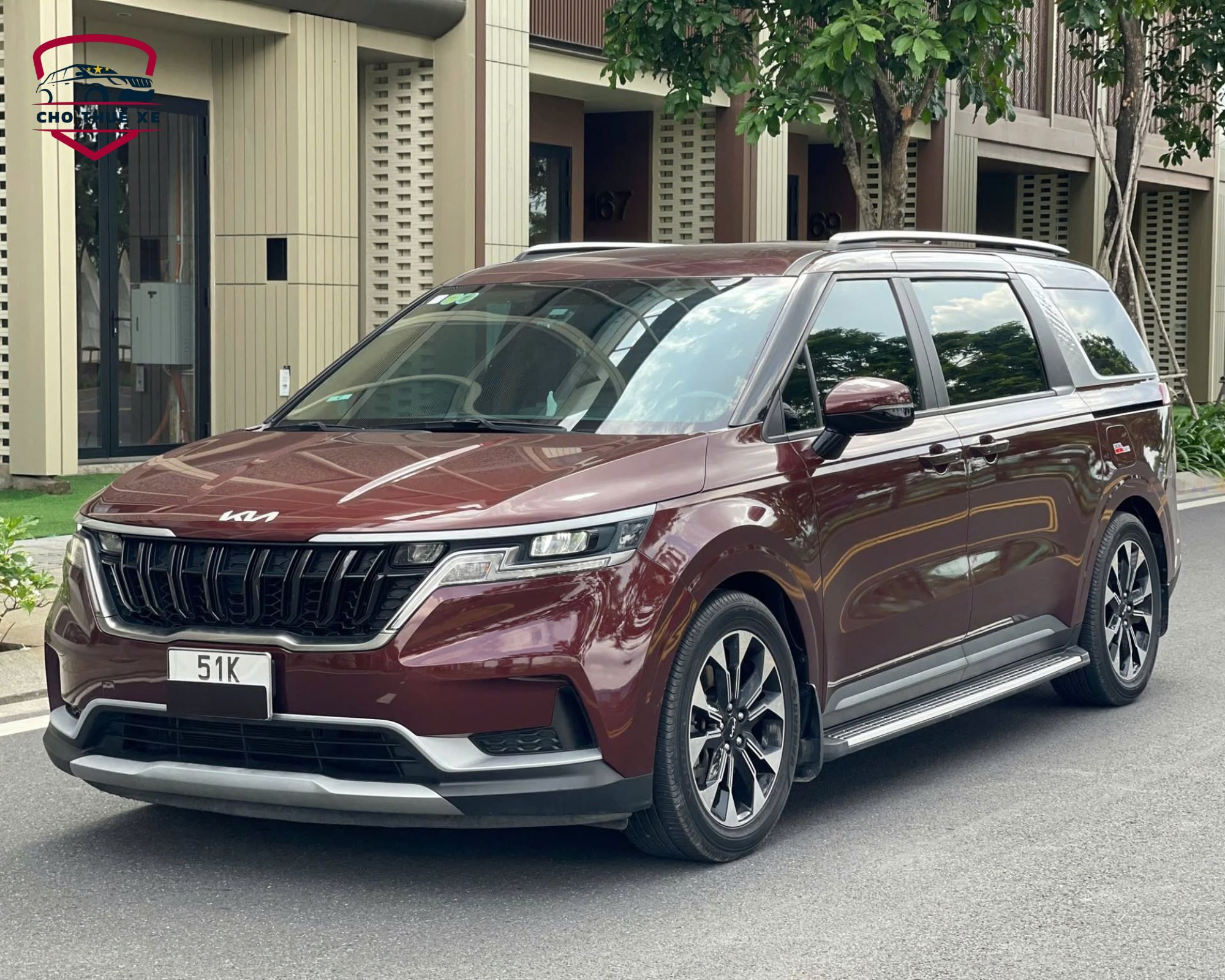Xe Kia Carnival thế hệ mới màu đỏ với lưới tản nhiệt đen thể thao đậu tại quận 2