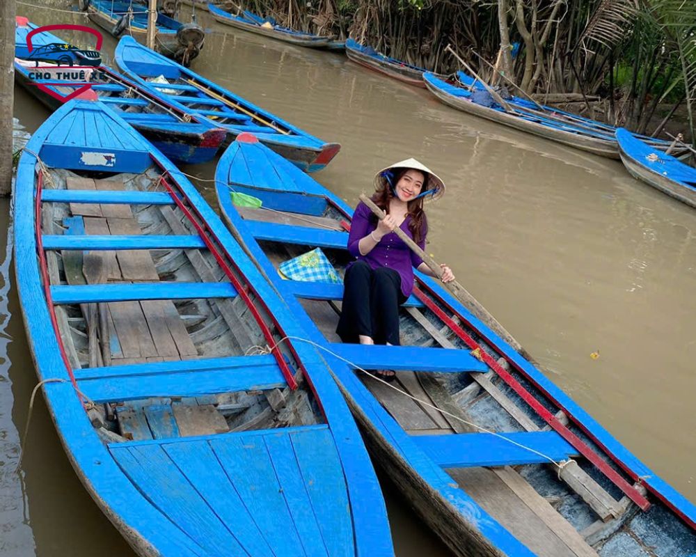 Người phụ nữ mặc áo bà ba và nón lá chèo đò trên sông nước Mỹ Tho