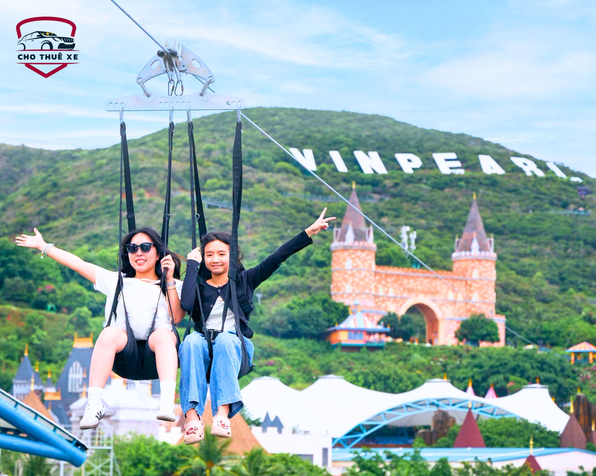 Hai cô gái trẻ đang vui vẻ chèo lượn trên tuyến zip line tại Vinpearl Nha Trang, cười tươi và dang rộng vòng tay tận hưởng cảm giác bay lượn